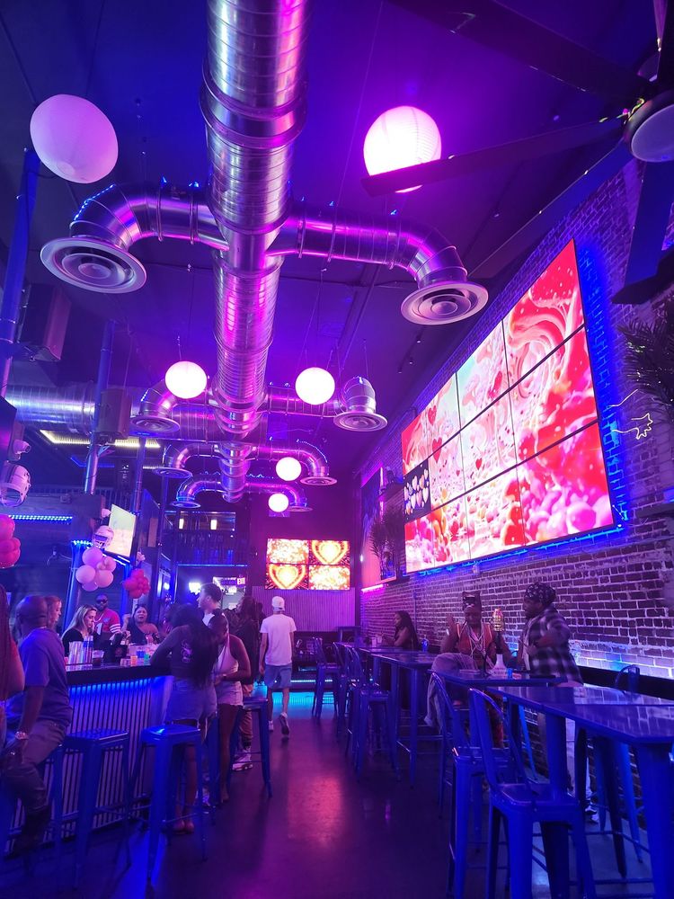 The neon-lit interior and large video wall at Papi’s